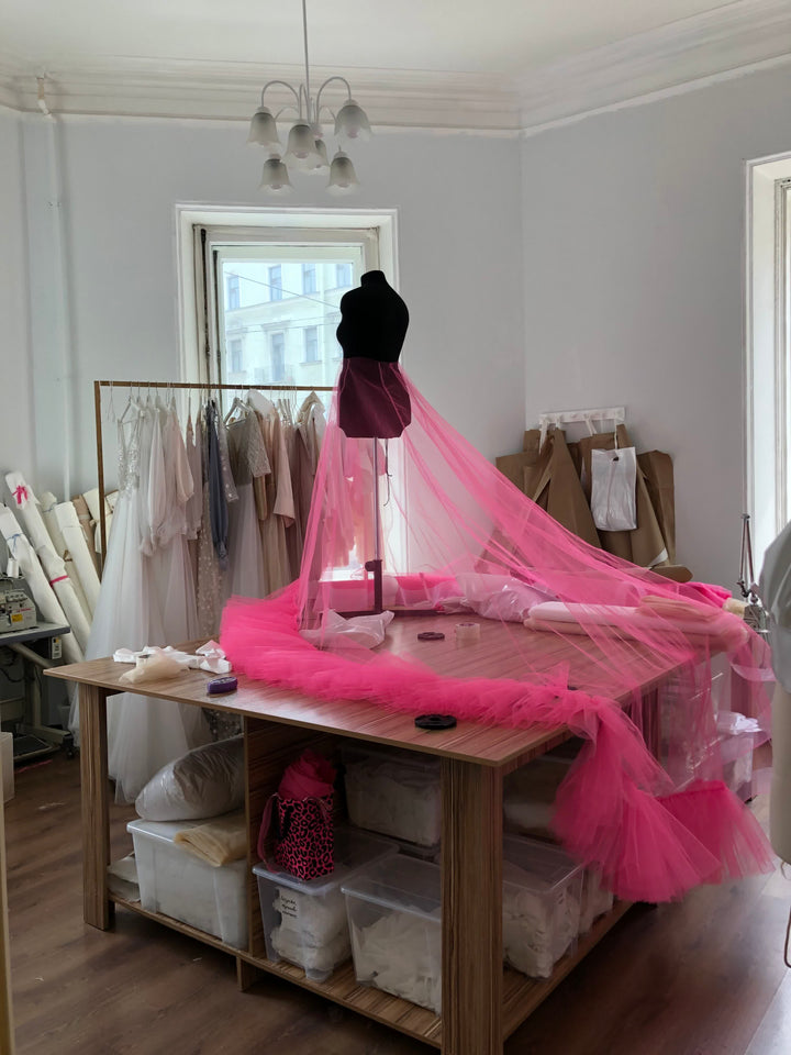 Bridal atelier production workspace in Ansignan, France, with pink tulle on the cutting table
