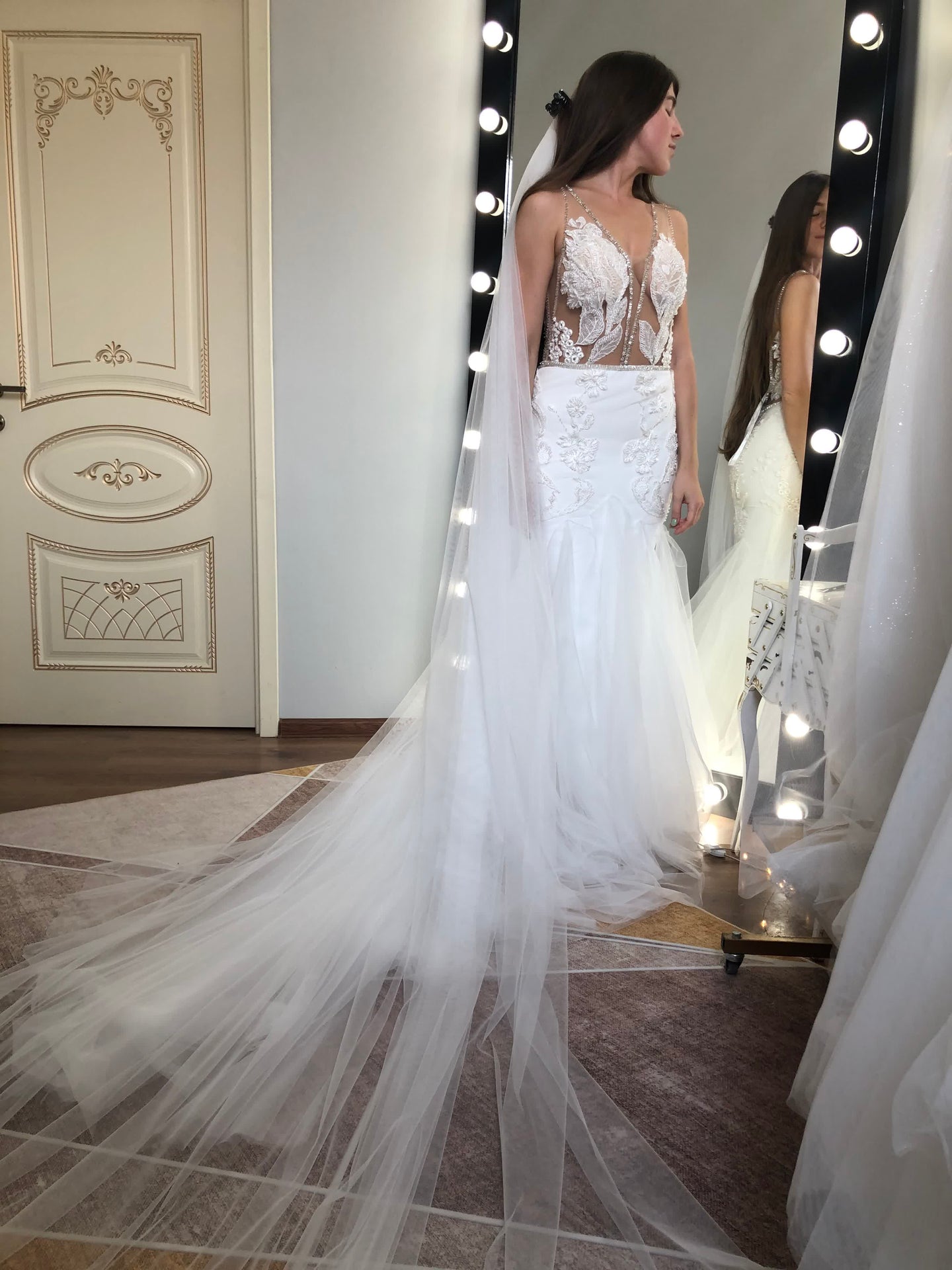 Illusion lace mermaid wedding dress, side profile, with a sweeping cathedral veil — editorial bridal detail showing neckline construction