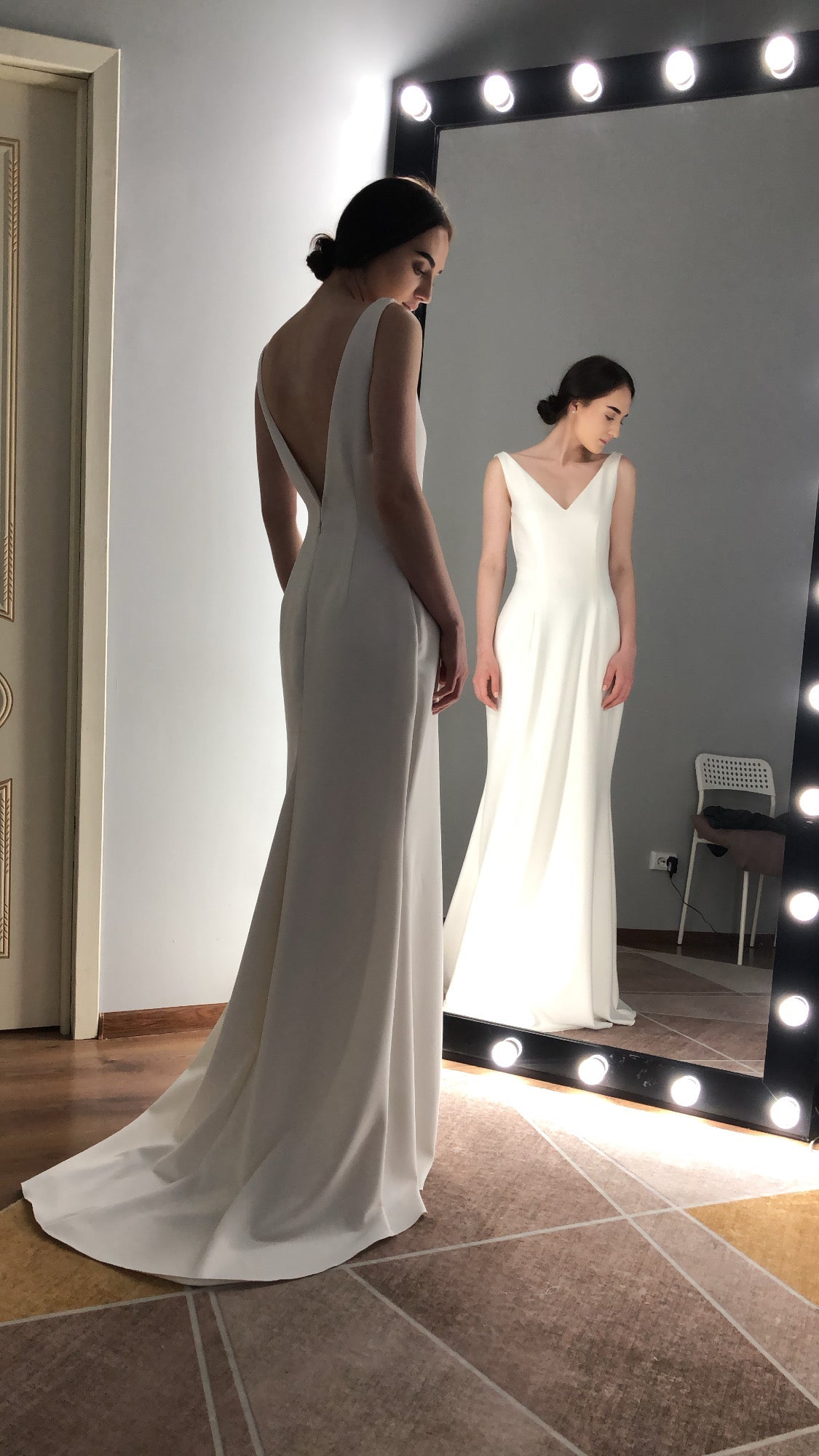 Minimalist ivory crepe wedding dress with open back and V-neck, mirror reflection — a quieter silhouette often chosen for a second wedding dress