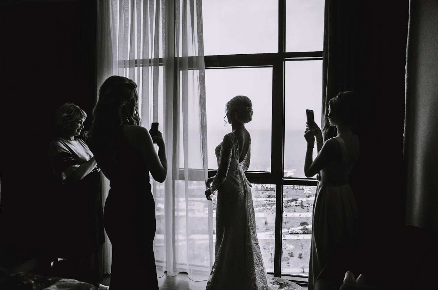 Silhouette of a bride in a wedding gown against bright light, full dress shape visible from head to floor