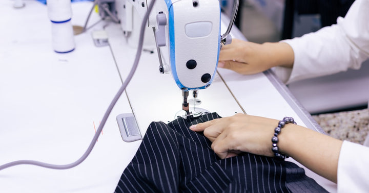 A seamstress at a sewing machine crafting a custom garment in a professional atelier setting